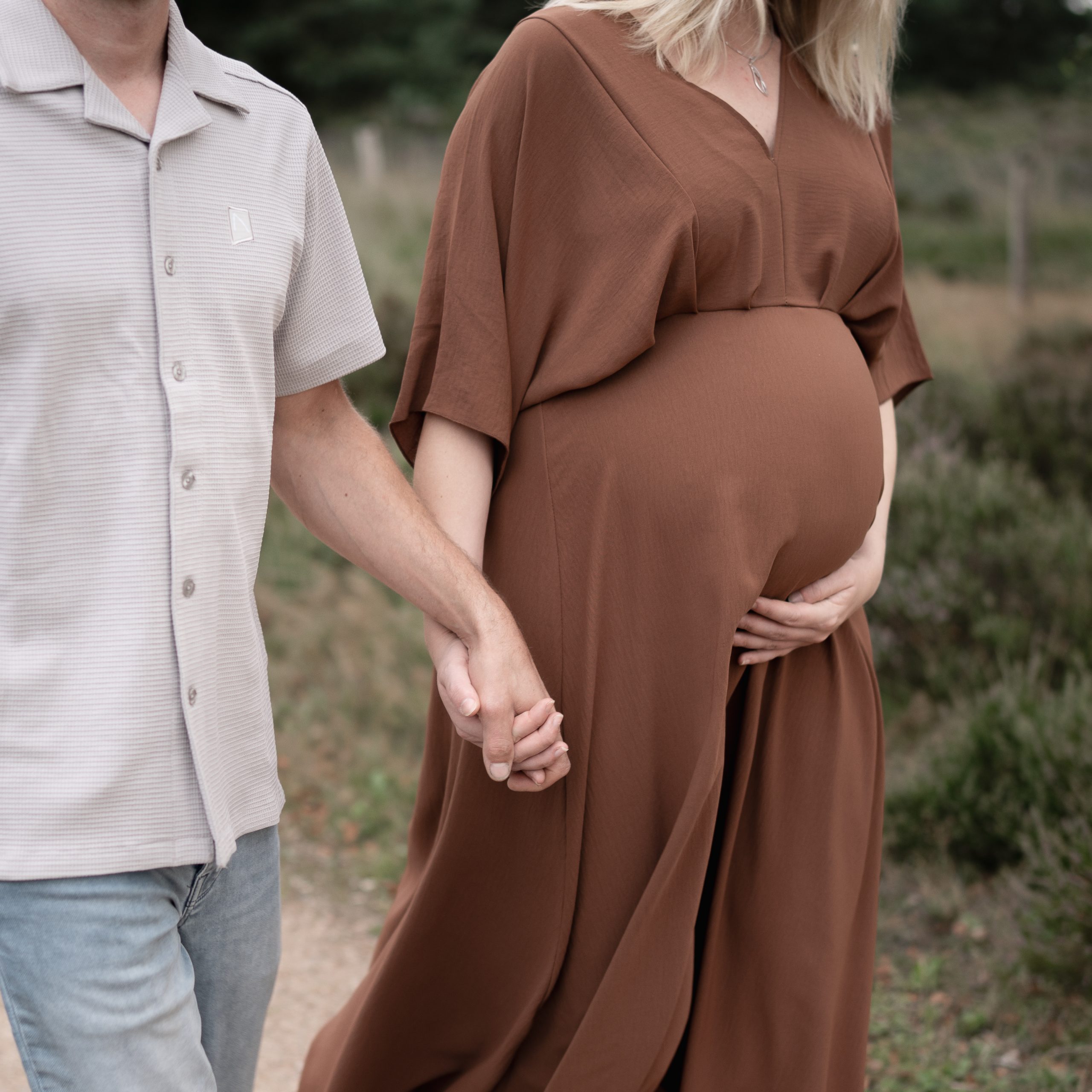 Marije Gerritsen Fotografie - Zwangerschapsshoot website-4 Aanstaande ouders tijdens een ontspannen zwangerschapsshoot in de natuur, met focus op details zoals handen op de buik.