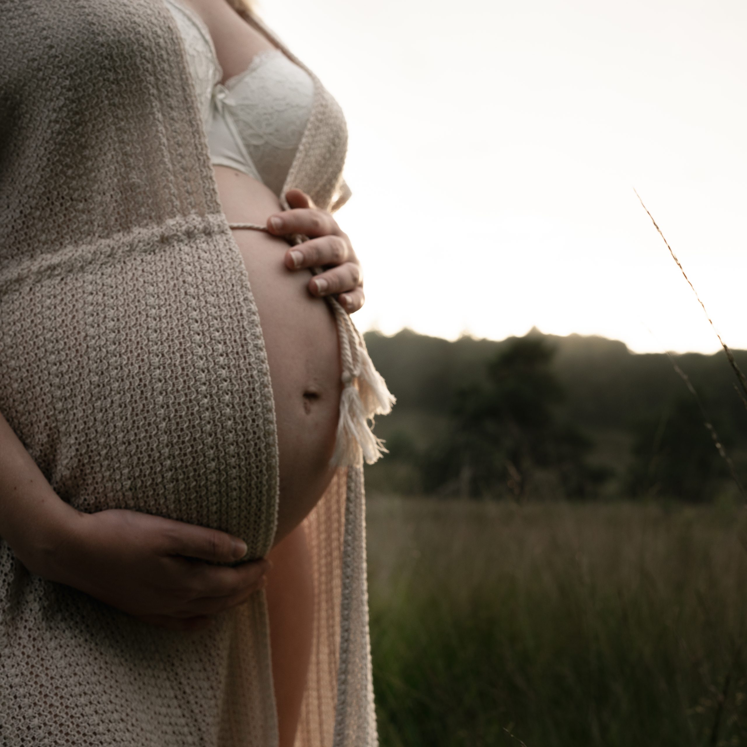 Marije Gerritsen Fotografie - Zwangerschapsshoot website-5 Aanstaande ouders tijdens een ontspannen zwangerschapsshoot in de natuur, met focus op details zoals handen op de buik