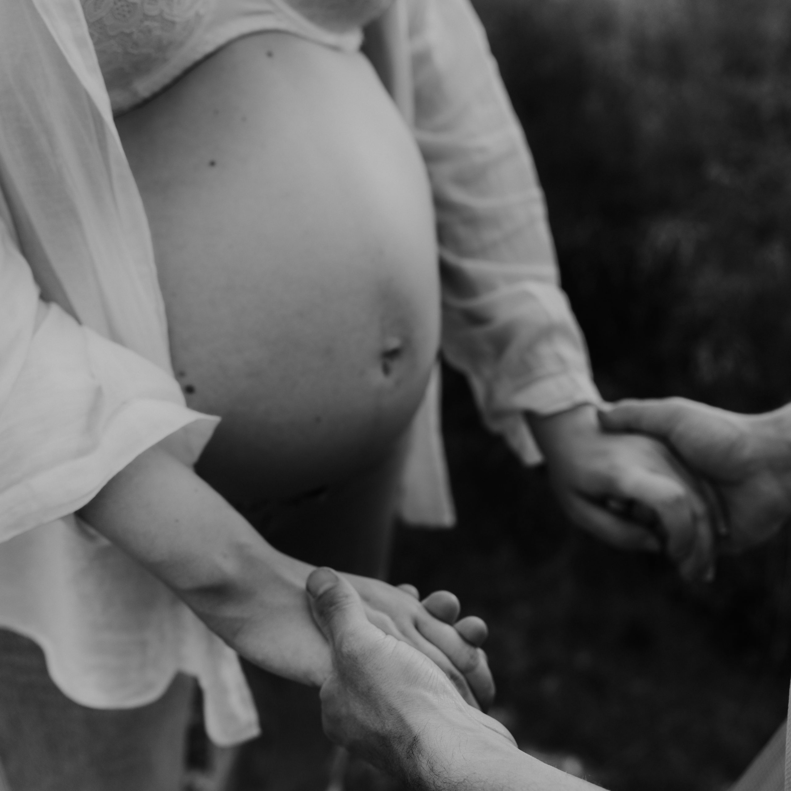 Marije Gerritsen Fotografie - Zwangerschapsshoot website-6 Aanstaande ouders tijdens een ontspannen zwangerschapsshoot in de natuur, met focus op details zoals handen op de buik